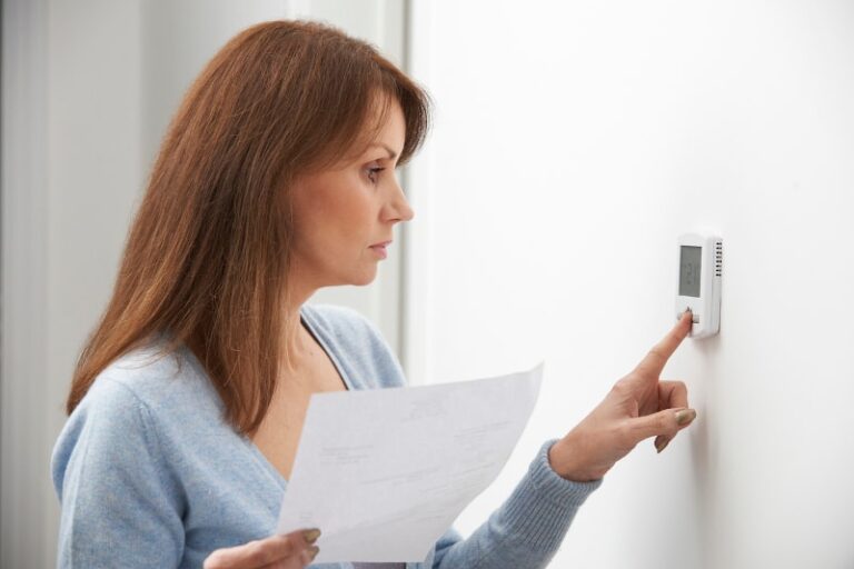 woman adjusting thermostat min
